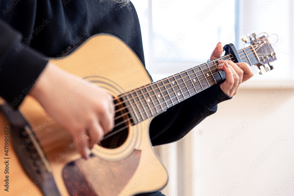 A woman plays an acoustic guitar, close-up.