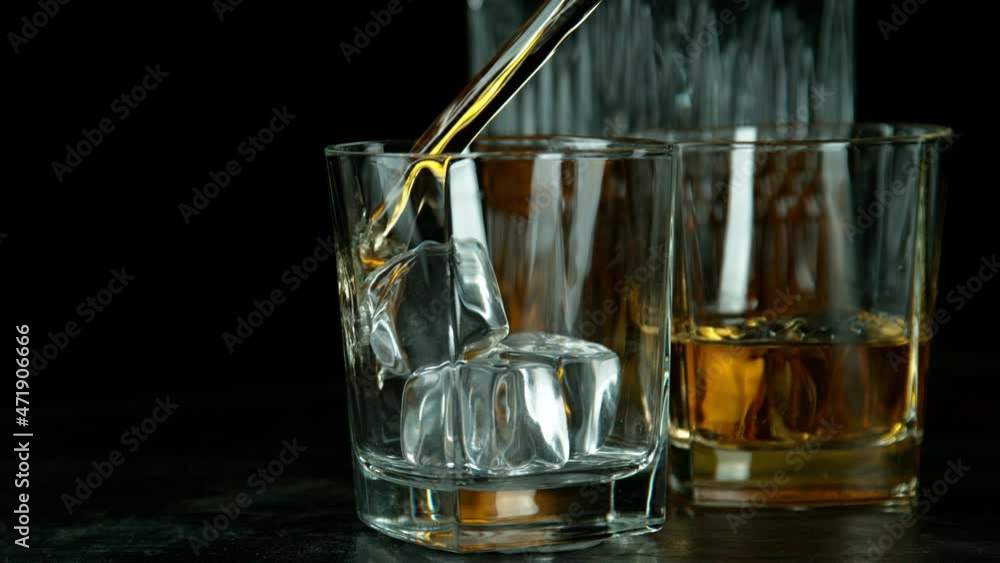 Super slow motion of pouring whiskey into glass with ice. Camera movement. Filmed on high speed cinema camera. Super slow motion of pouring whiskey into glass with ice. Camera movement. Filmed on high speed cinema camera.