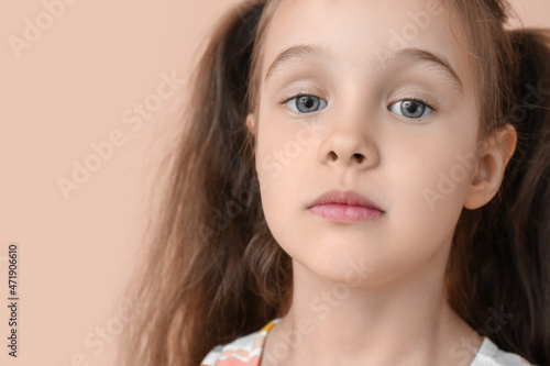 Portrait of cute little girl with ponytails on beige background, closeup