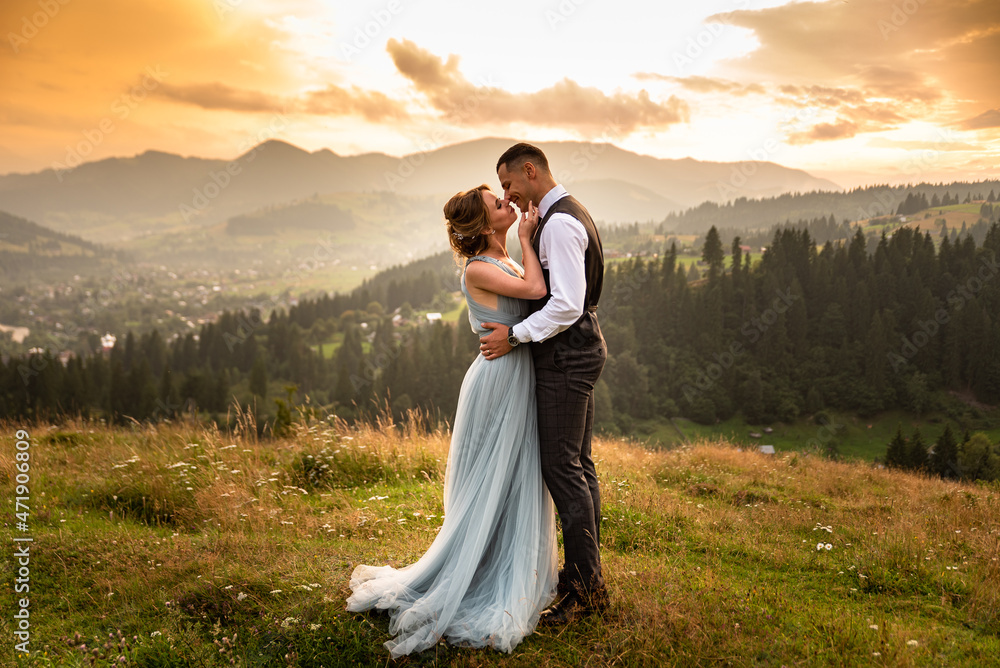 Wedding in the mountains. Beautiful couple of brides kissing standing on a mountain on a background of sunset in the mountains. Wedding in the mountains. Beautiful couple of brides kissing standing on a mountain on a background of sunset in the mountains.