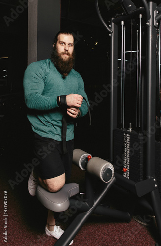 Bearded muscular man preparing for exercise in gym. Strong and handsome man with the beard. © lizaPolovinko