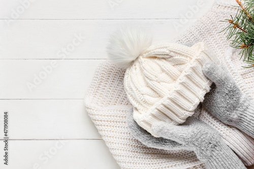 Woman in gloves with hat and sweater on white wooden background. Winter concept