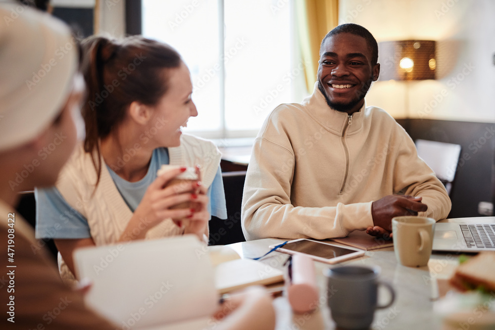 Group of students drinking coffee and laughing while working together at the table Group of students drinking coffee and laughing while working together at the table