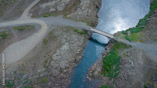 Bridge over river in iceland. Direct overhead aerial view of a bridge spanning over still water.