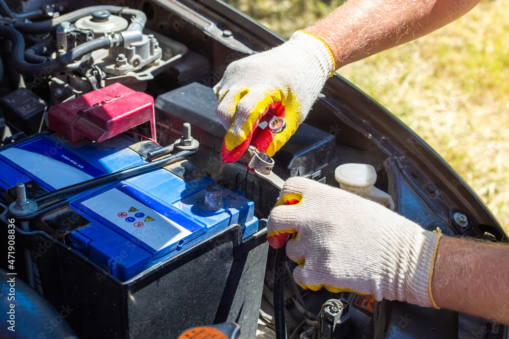 The car mechanic unscrews the car battery holder to repair or replace