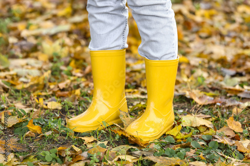 Woman in yellow gumboots in autumn park