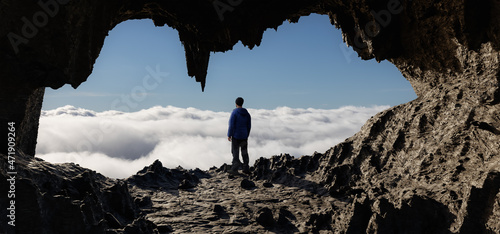 Dramatic Adventurous Scene with Man standing inside an Alien like Rocky Cave Landcspae. 3d Rendering Art. Aerial Cloudscape Image from British Columbia, Canada. Adventure Concept photo