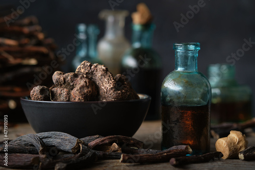 Bottles of infusion or tincture of Persicaria bistorta and Common comfrey roots. Bowl of Bistort, Snakeweed, Snake roots. Dry comfrey officinalis roots also known as symphytum officinale, knitbone. photo