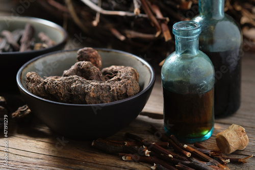 Bottles of infusion or tincture of Persicaria bistorta and Common comfrey roots. Bowl of Bistort, Snakeweed, Snake roots. Dried comfrey officinalis roots also known as symphytum officinale, knitbone. photo