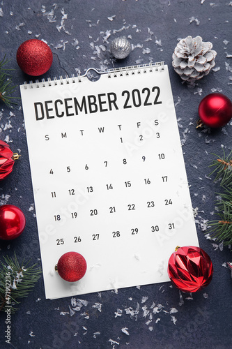 Paper calendar for December 2022 and Christmas decor on dark background