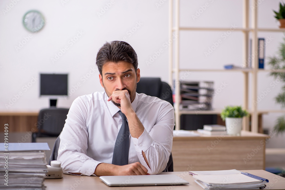 Young male employee and too much work in the office Young male employee and too much work in the office