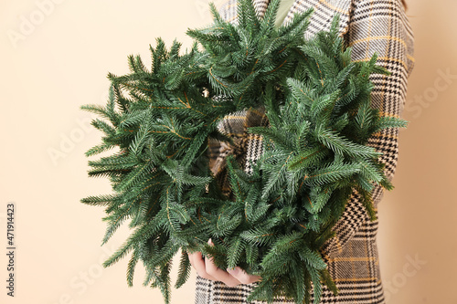 Fototapeta Naklejka Na Ścianę i Meble -  Woman holding Christmas wreath on beige background