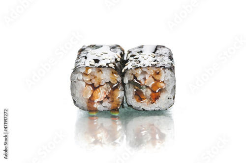 Two pieces of Japanese Unagi Maki sushi roll with nori seaweed on top. Eel inside roll served with sauce. Side view of inside out roll isolated on white background. Copy space image with reflection 