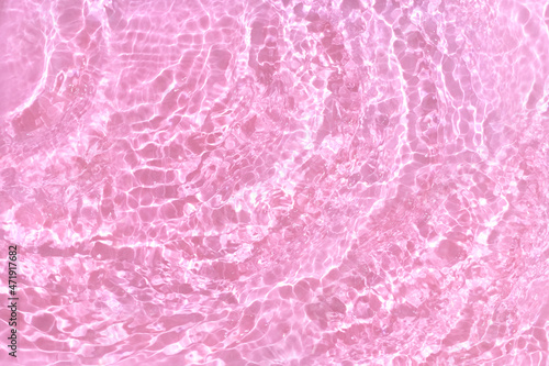 Transparent pink water background. Sun, shadows and ripples. Summer concept. Top view
