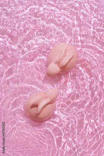 Happy Easter minimal concept. Two bunny rabbits in water on pastel pink background 