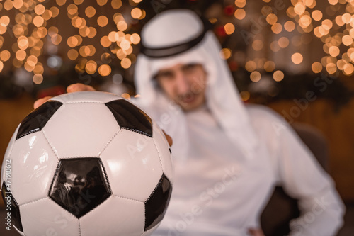 portrait of arab businessman showing a soccer ball in front of lights © Marino Bocelli