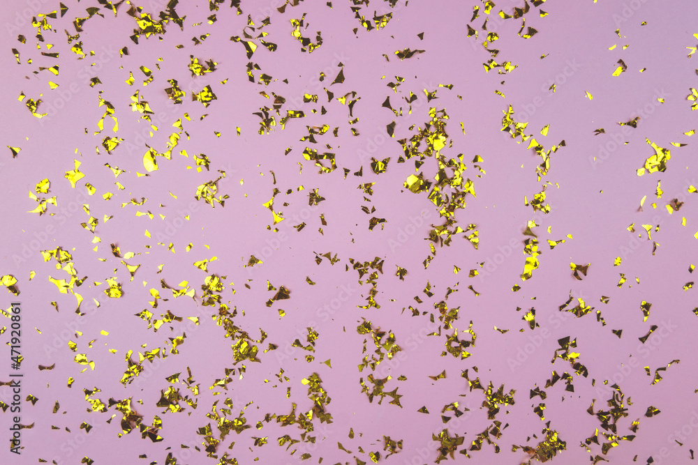 Golden glittering confetti on a pink backgroung. Festive backgroung