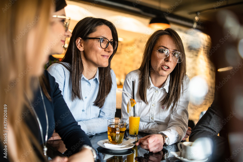 Group of female friends sitting by the table at restaurant having fun talking - adult millennial women at cafe chatting spending time together real people friendship concept