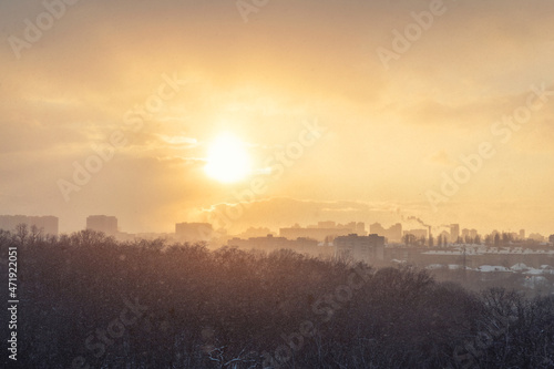Aerial drone top view of scenic warm sunrise morning sun shine through snowstorm vortex blizzard against city building cityscape panoramic urban background. Winter snowfall storm and sunny weather