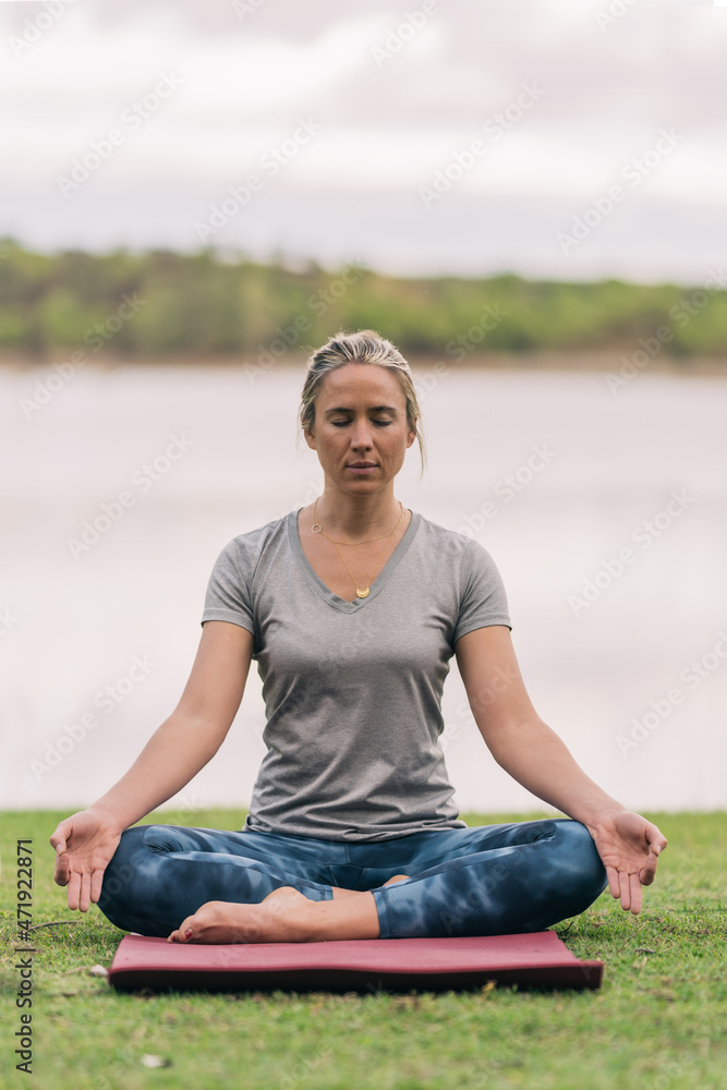 Blonde fit woman doing the yoga lotus position outdoors