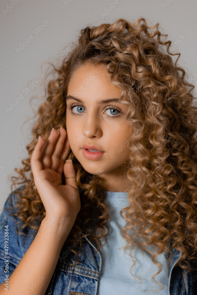 portrait of a cute smiling blonde girl with blue eyes and curly hair in a denim jacket. young woman with beautiful clean healthy skin. natural make up, spa concept, fashion concept. High quality photo