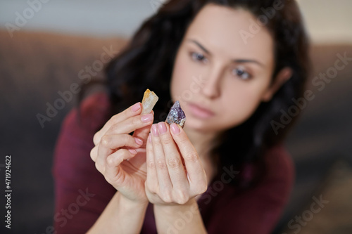 Focused young female scrutinizing citrine and amethyst