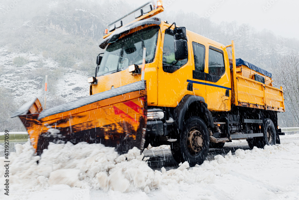 Moving snow plow truck removing snow from a snowy road. Moving snow plow truck removing snow from a snowy road.