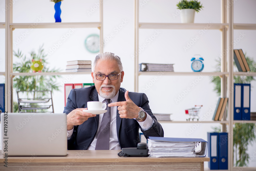 Old male employee drinking coffee during break Old male employee drinking coffee during break