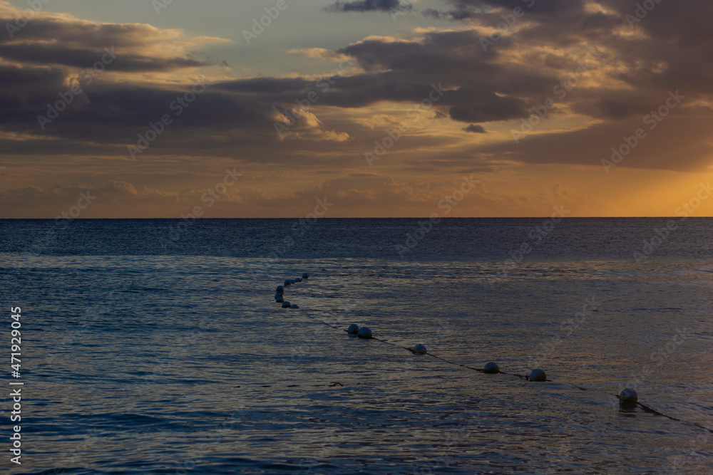 SUNSET ON THE BEACH WITH ORANGE LIGHT AND BLUE SKY WITH SOME CLOUDS