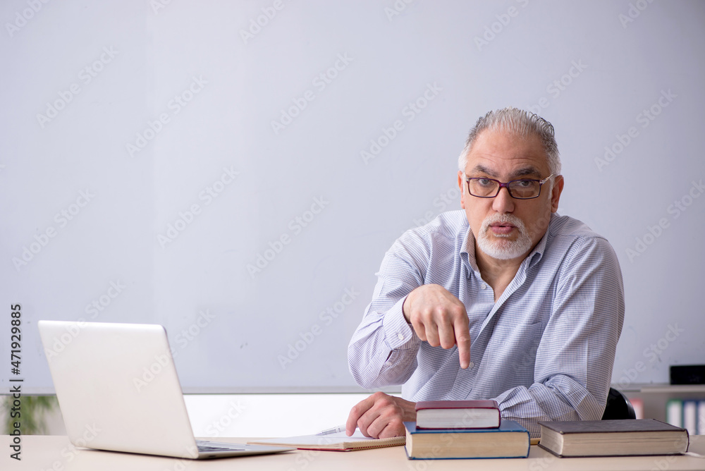 Old male teacher in front of whiteboard Old male teacher in front of whiteboard