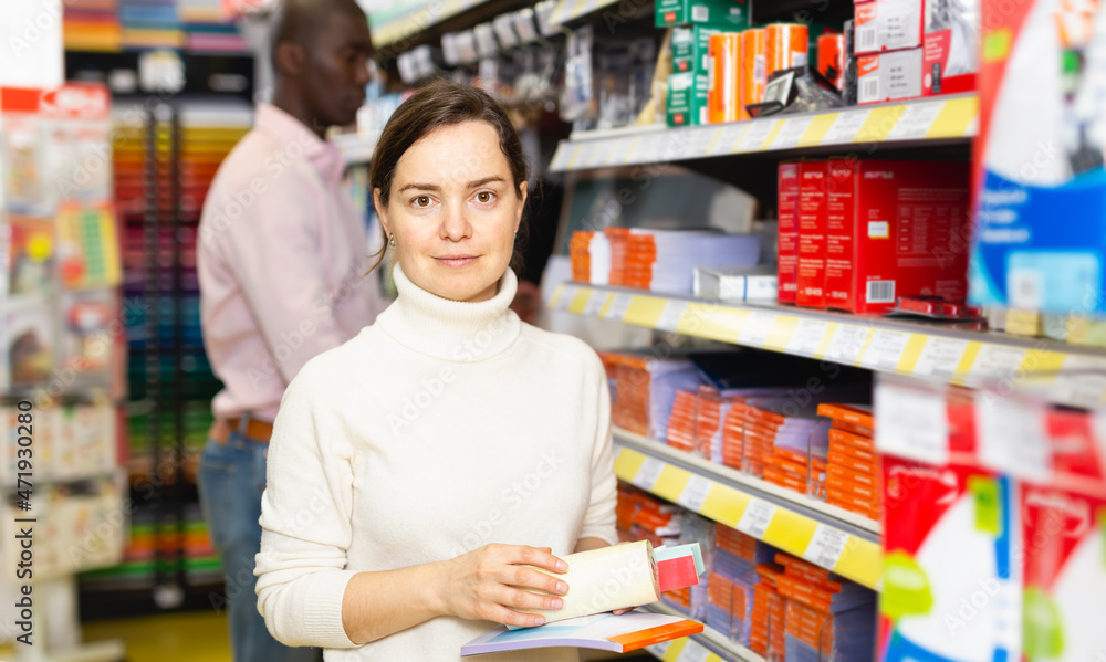 Young woman holding office supplies at stationery store