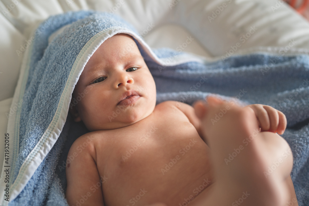Small caucasian baby boy lying down on in the blue towel after bathing at home naked waiting to get dressed domestic life infant hygiene daily routine concept Small caucasian baby boy lying down on in the blue towel after bathing at home naked waiting to get dressed domestic life infant hygiene daily routine concept