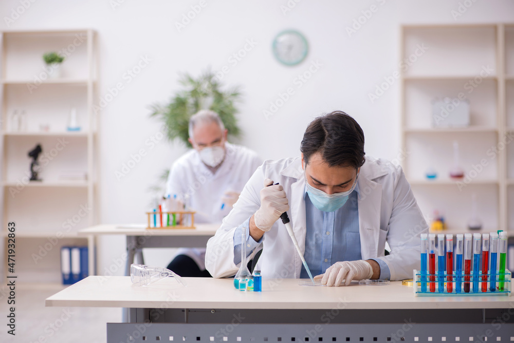 Naklejka premium Two male chemists working at the lab during pandemic