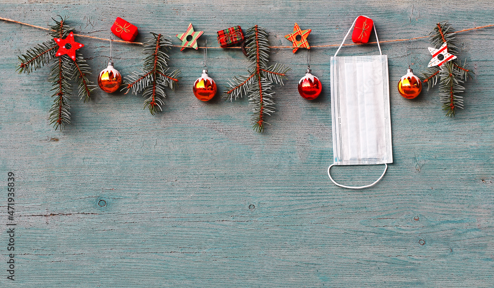 Corona und Weihnachten. Eine Schutzmaske hängt neben Christbaumkugeln,  Tannenzweigen, Geschenkpäckchen und Sternen Stock Photo | Adobe Stock