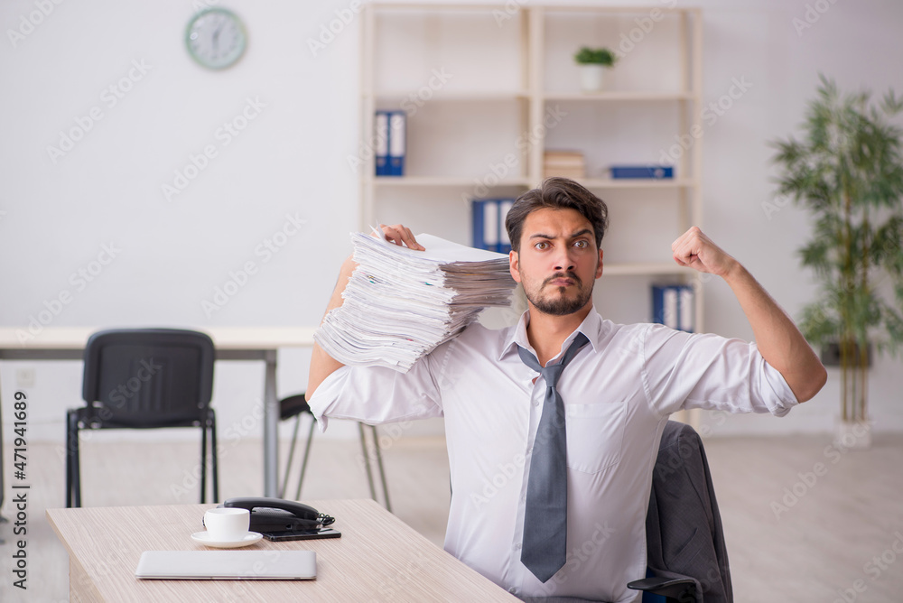 Young male employee and too much work in the office Young male employee and too much work in the office