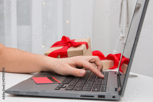 Hands of a young woman using a laptop. Christmas online shopping concept.