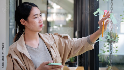 Thought creative designer putting sticky notes on glass window.