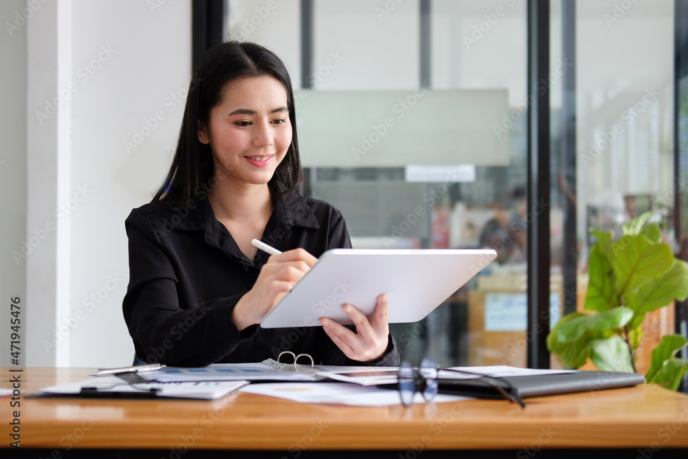 Smiling beautiful businesswoman holding stylus pen and writing information on digital tablet. Smiling beautiful businesswoman holding stylus pen and writing information on digital tablet.