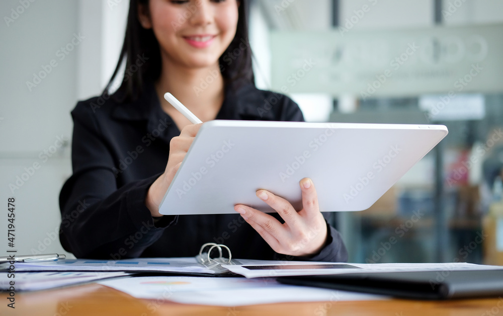 Happy business woman using stylus pen writing some information on digital tablet. Happy business woman using stylus pen writing some information on digital tablet.