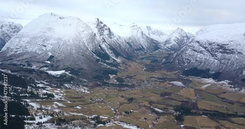 An amazing, deep valley surrounded by majestic, snowy mountains are revealed in this high altitude, forward flying aerial drone time lapse in muted, autumn colors in western Norway. photo