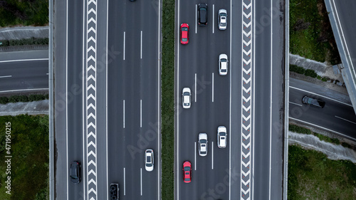 Top down aerial view from drone on modern traffic junction of multiple lane highway road in metropolis city. Heavy traffic on motorways. Elevated curved roads, clover shape bridge with no speed limit.