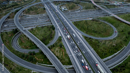 Top down aerial view from drone on modern traffic junction of multiple lane highway road in metropolis city. Heavy traffic on motorways. Elevated curved roads, clover shape bridge with no speed limit.