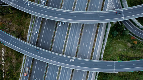 Top down aerial view from drone on modern traffic junction of multiple lane highway road in metropolis city. Heavy traffic on motorways. Elevated curved roads, clover shape bridge with no speed limit.