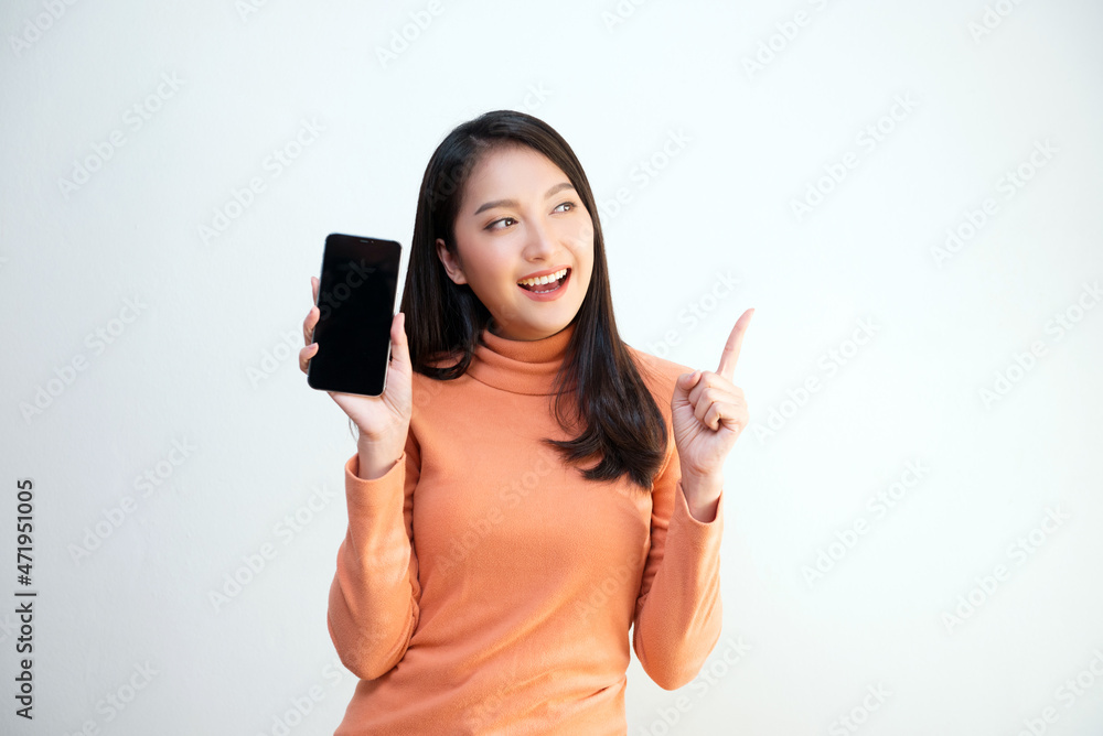 Attractive Asian girl portrait, wearing orange shirt, holding smartphone, smiling face, showing emotion, for communication, advertisement, copy space. Attractive Asian girl portrait, wearing orange shirt, holding smartphone, smiling face, showing emotion, for communication, advertisement, copy space.