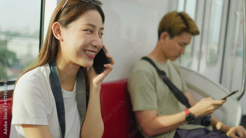 Asian woman relaxing in train seat while using smartphone app. Chinese businesswoman enjoying view texting on mobile phone. Travel lifestyle. Asian woman relaxing in train seat while using smartphone app. Chinese businesswoman enjoying view texting on mobile phone. Travel lifestyle.