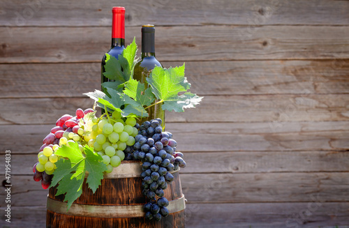 Various colorful grapes and wine bottles on wine barrel