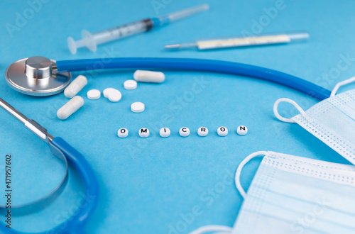 Omicron variant text, syringe, stethoscope and face masks on blue background