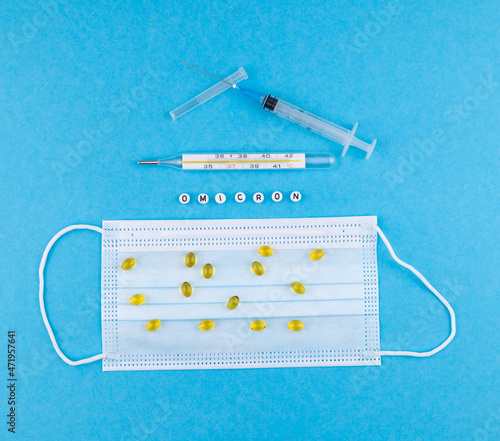 medical mask, syringe, medicines, thermometer and the word omicron