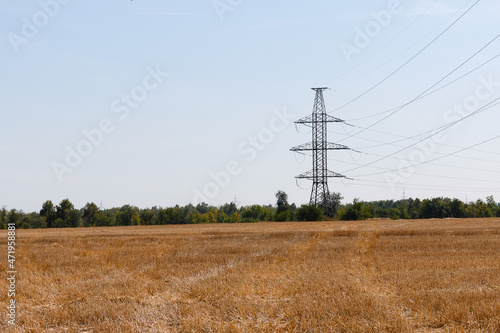 power line in the field, supports of high-voltage wires, autumn field of harvested crops