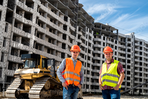 two young workers in uniform stand on the background of a new building